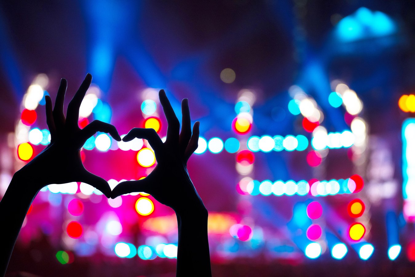 Concert crowd raising heart shaped hands at concert